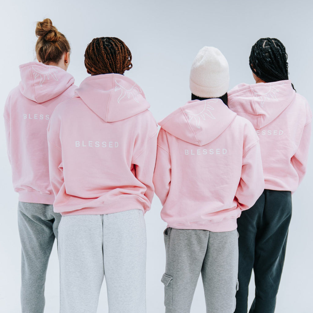 Four people wearing pink hoodies and  white background