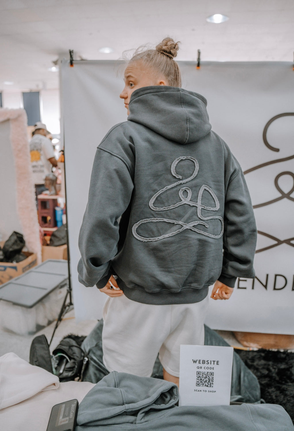 Woman wearing grey “Free Mind” hoodie from the back, part of ENDEN BRAND’s affirmation-based streetwear collection.
