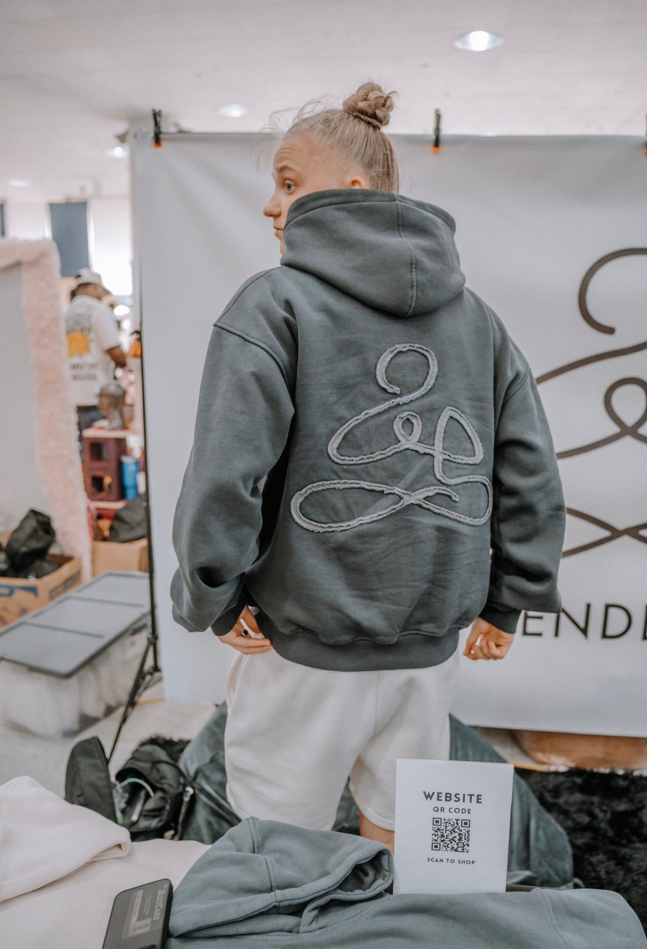 Woman wearing grey “Free Mind” hoodie from the back, part of ENDEN BRAND’s affirmation-based streetwear collection.
